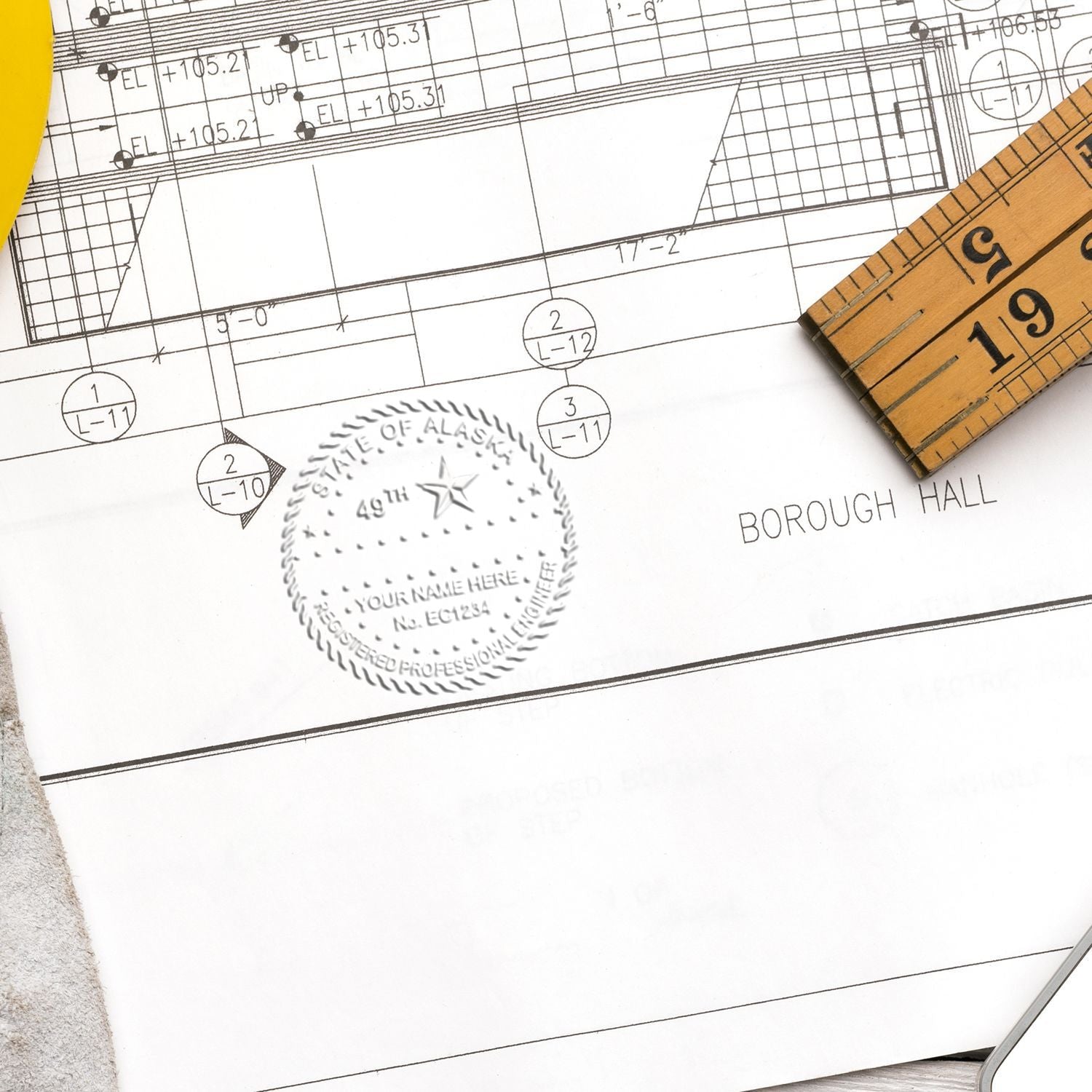 Alaska Embossed Seal Image on Paper: An embossed seal of Alaska on a document with a ruler and architectural plans in the background.