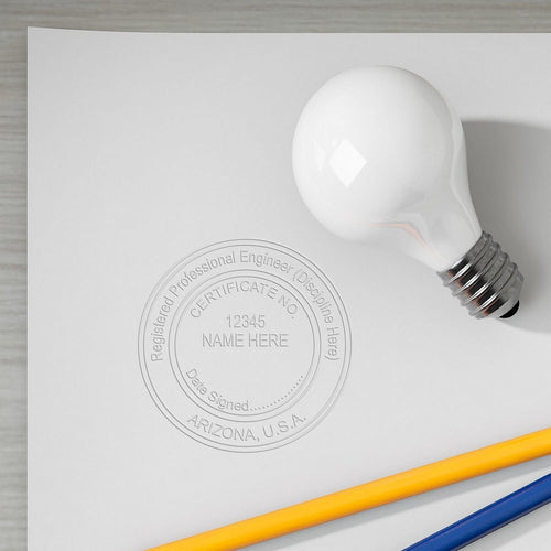 Arizona PE Stamp image on paper with a light bulb and pencils placed on it.