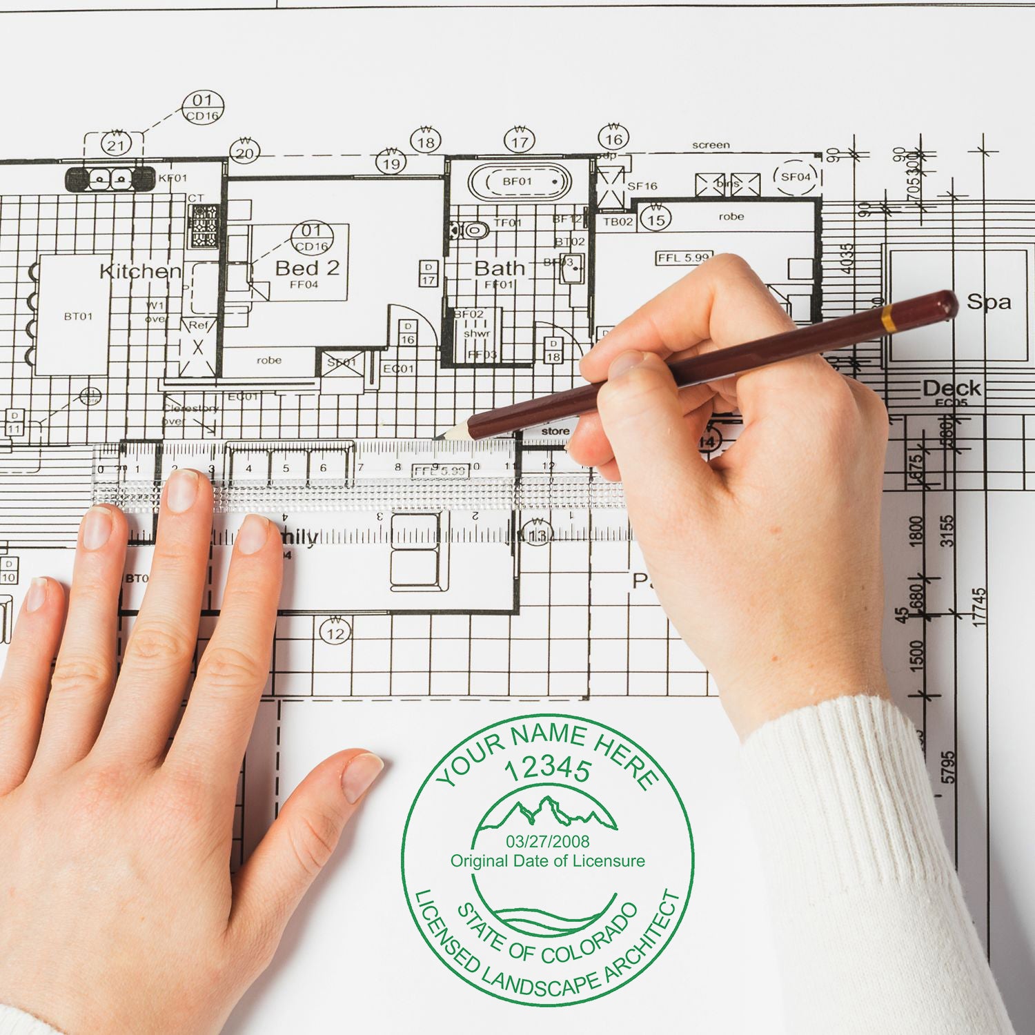 Hands working on a detailed architectural blueprint with a Colorado Landscape Architect seal stamp. Blog post: Colorado Landscape Architect Feature Image.