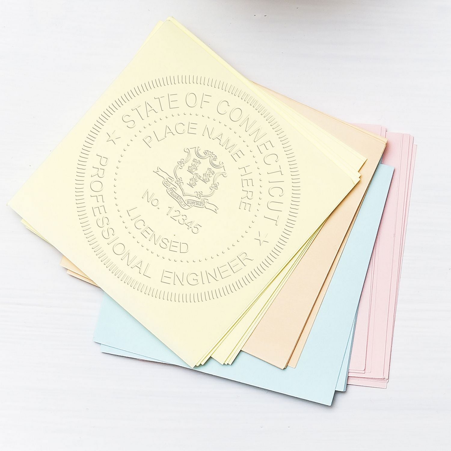 Connecticut Engineer Embossing Seal in use on a stack of pastel-colored papers. Blog post: Connecticut Engineer Embossing Seal.