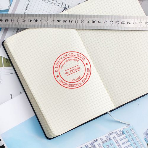 Alt Text: Feature Image for DC PE Seal: Open notebook with District of Columbia Professional Engineer seal stamp, ruler, and architectural plans.