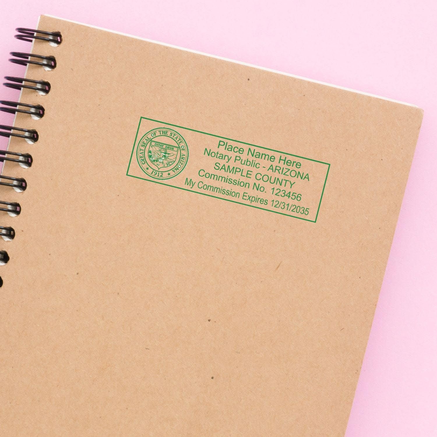 Arizona Notary Supplies Blog Post Feature Image: Rectangular notary stamp on a spiral notebook with a pink background.