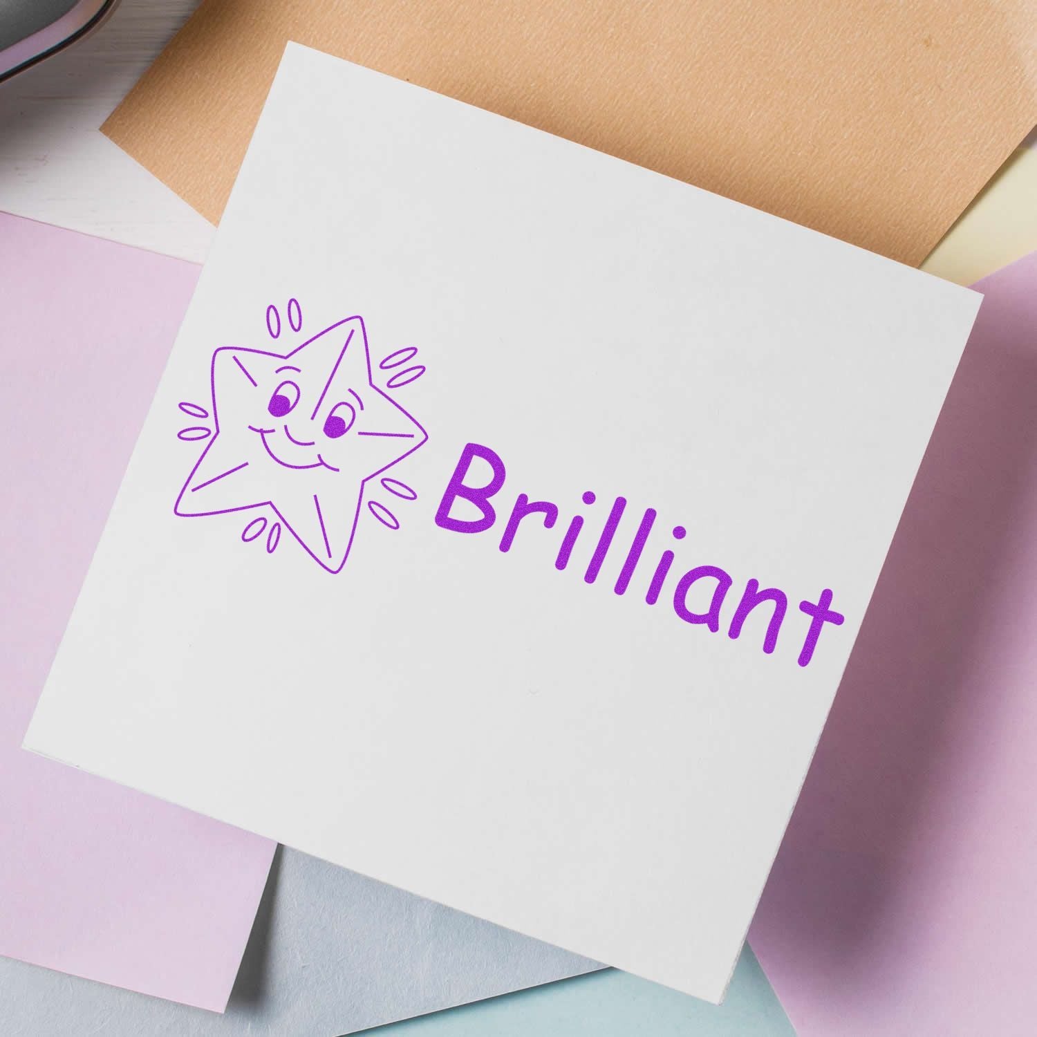 Teacher Stamps for Kids Blog Post Feature Image: A white card with a purple star stamp and the word 'Brilliant' on pastel papers.