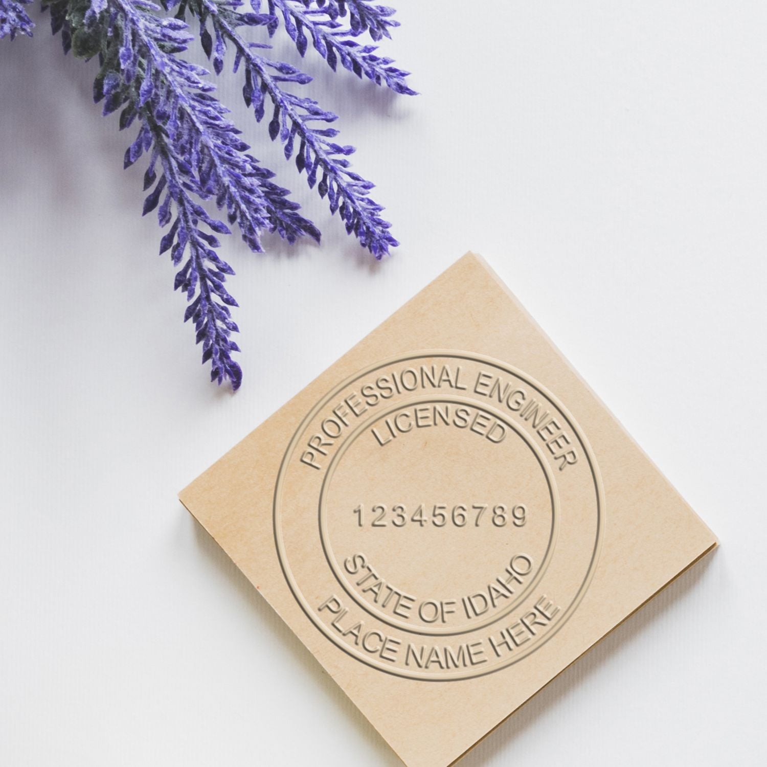 Image of an Idaho Professional Engineer Embosser Stamp on a beige surface with lavender flowers. Blog post: Idaho Professional Engineer Embosser Stamp.