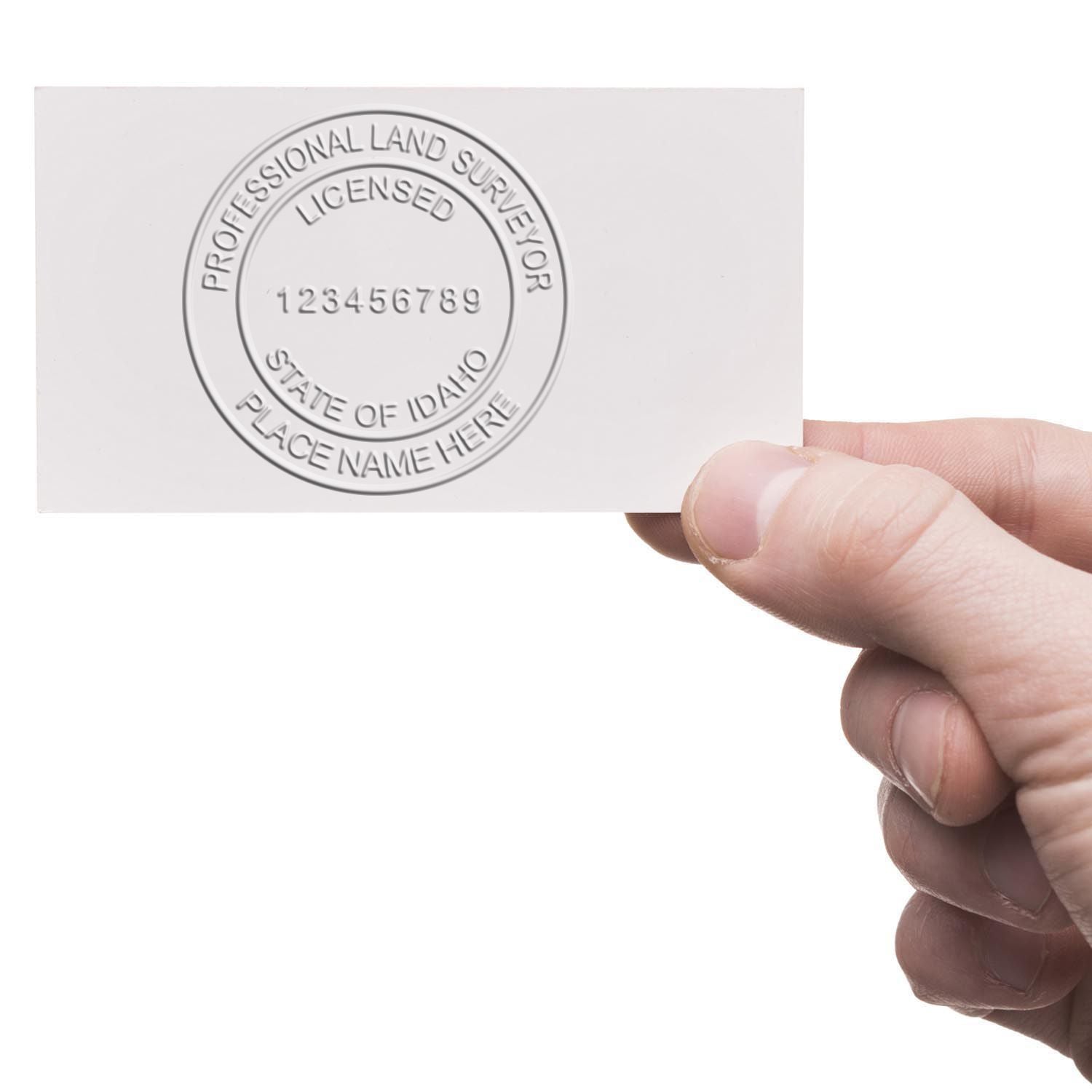 Hand holding a card with an embossed Idaho Land Surveyor Seal. Blog post: Idaho Land Surveyor Seals.