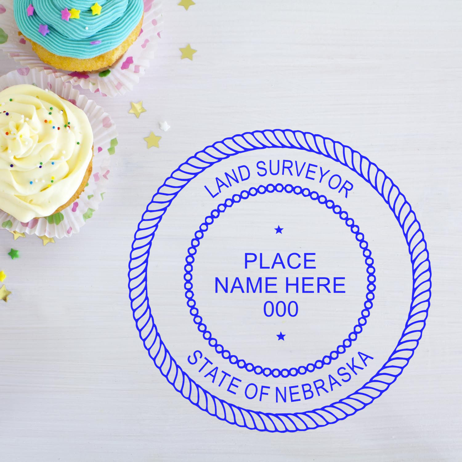 Cupcakes beside a Nebraska Land Surveyor seal stamp on a white surface. Blog post: Nebraska Land Surveyor Seals.