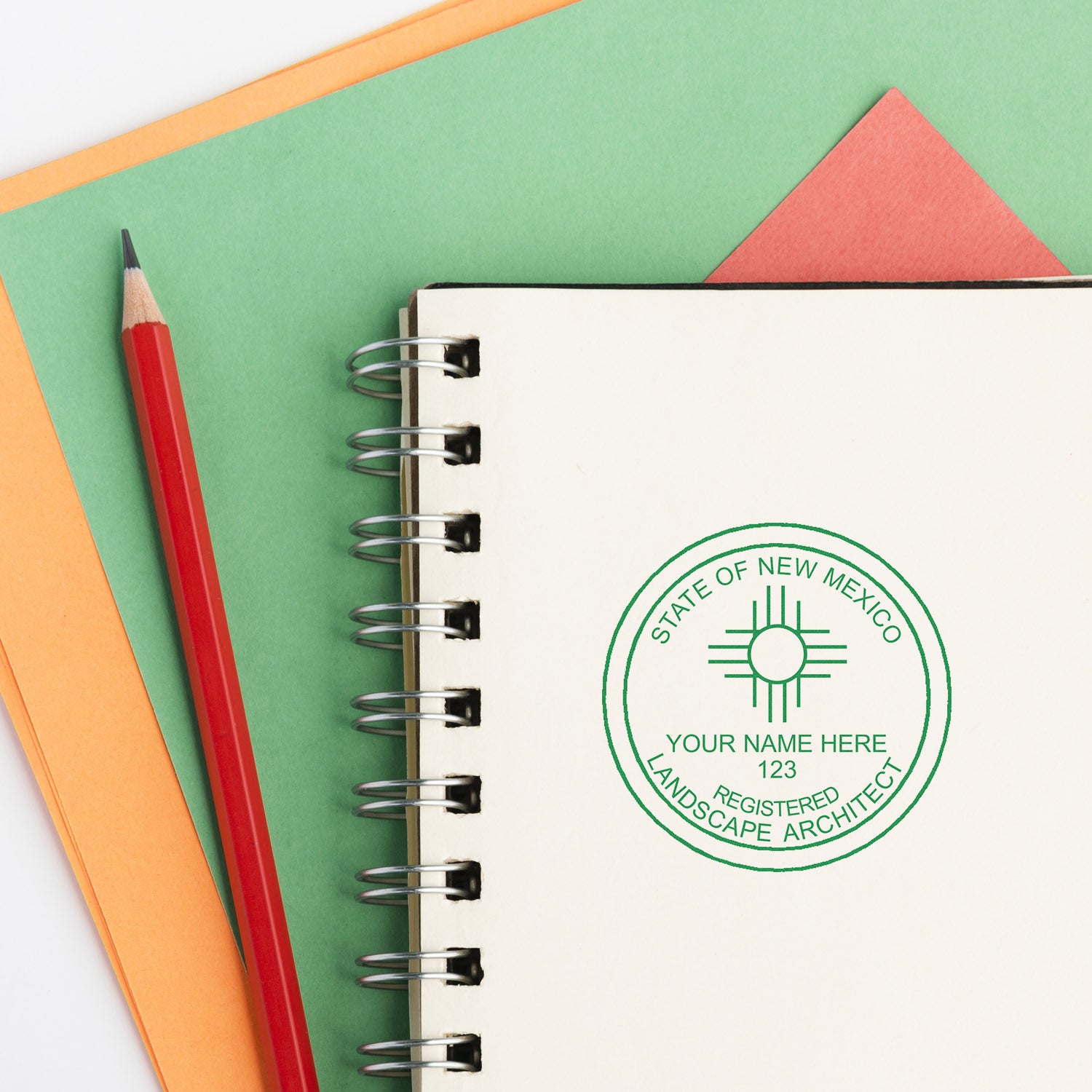 New Mexico Landscape Architect Feature Image: A spiral notebook with a green New Mexico landscape architect seal, red pencil, and colored papers.