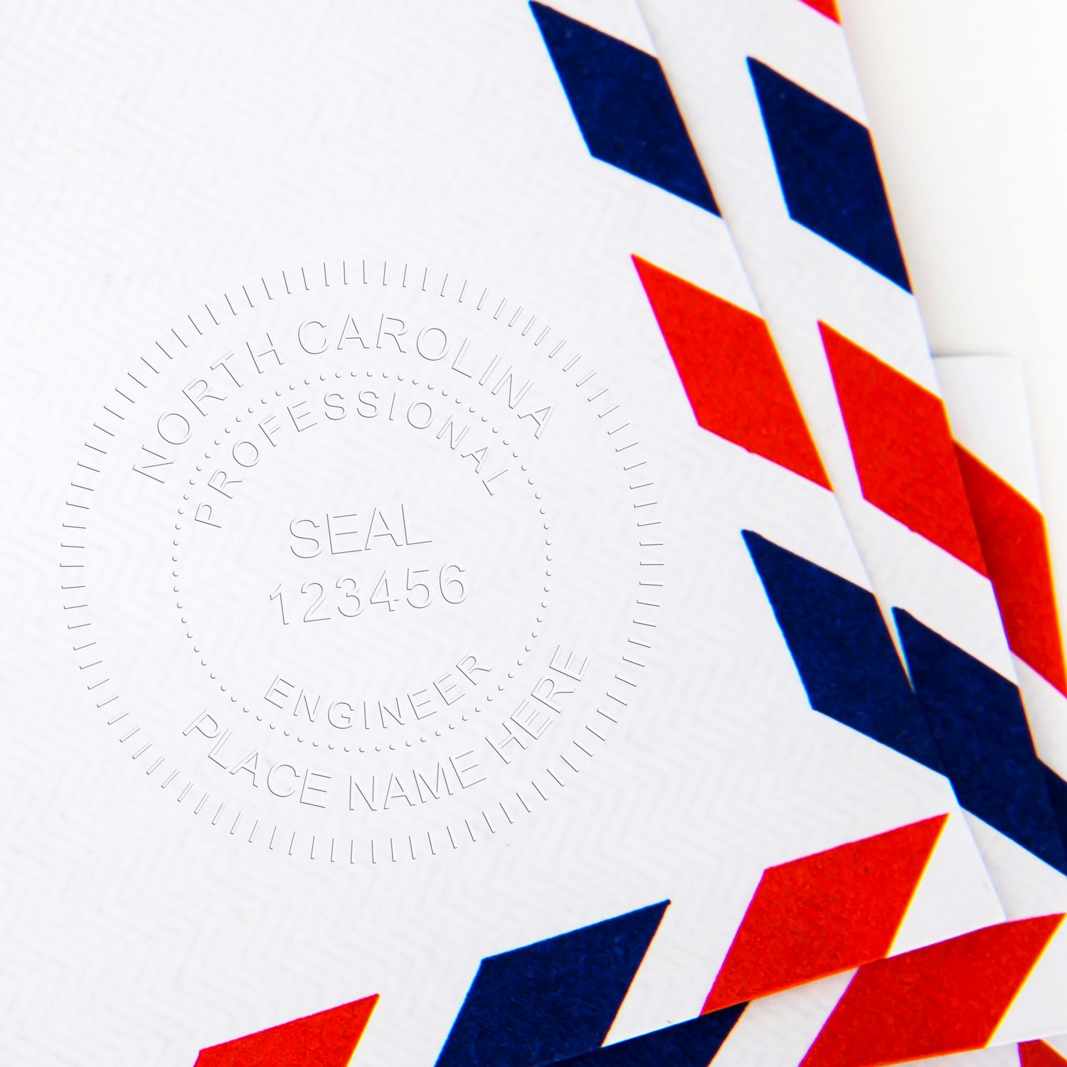 Embossed North Carolina professional engineer seal on a document with red, blue, and white chevron pattern. Blog post: North Carolina Seals.