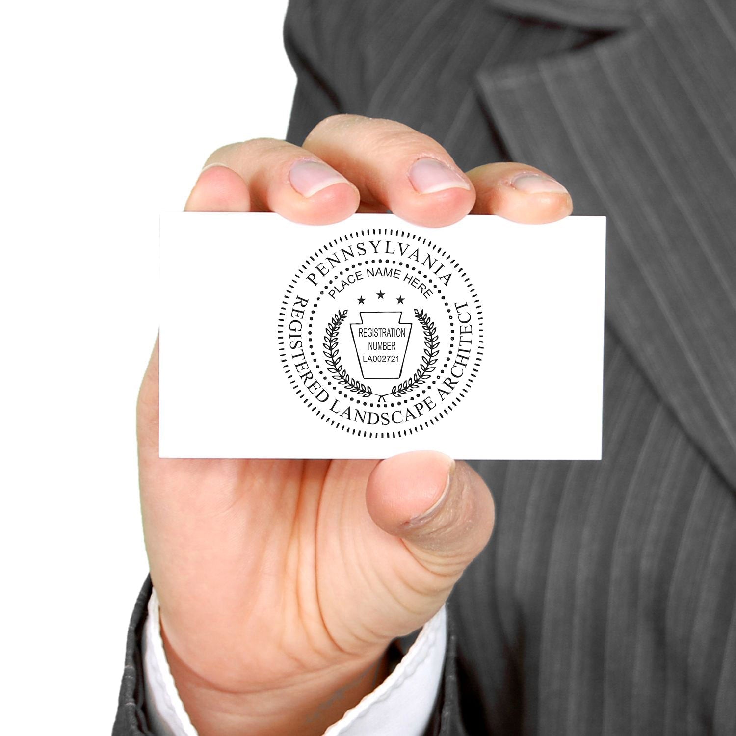 Person in a suit holding a business card with a Pennsylvania Registered Landscape Architect seal. Blog post: Pennsylvania Landscape Architect Feature Image.