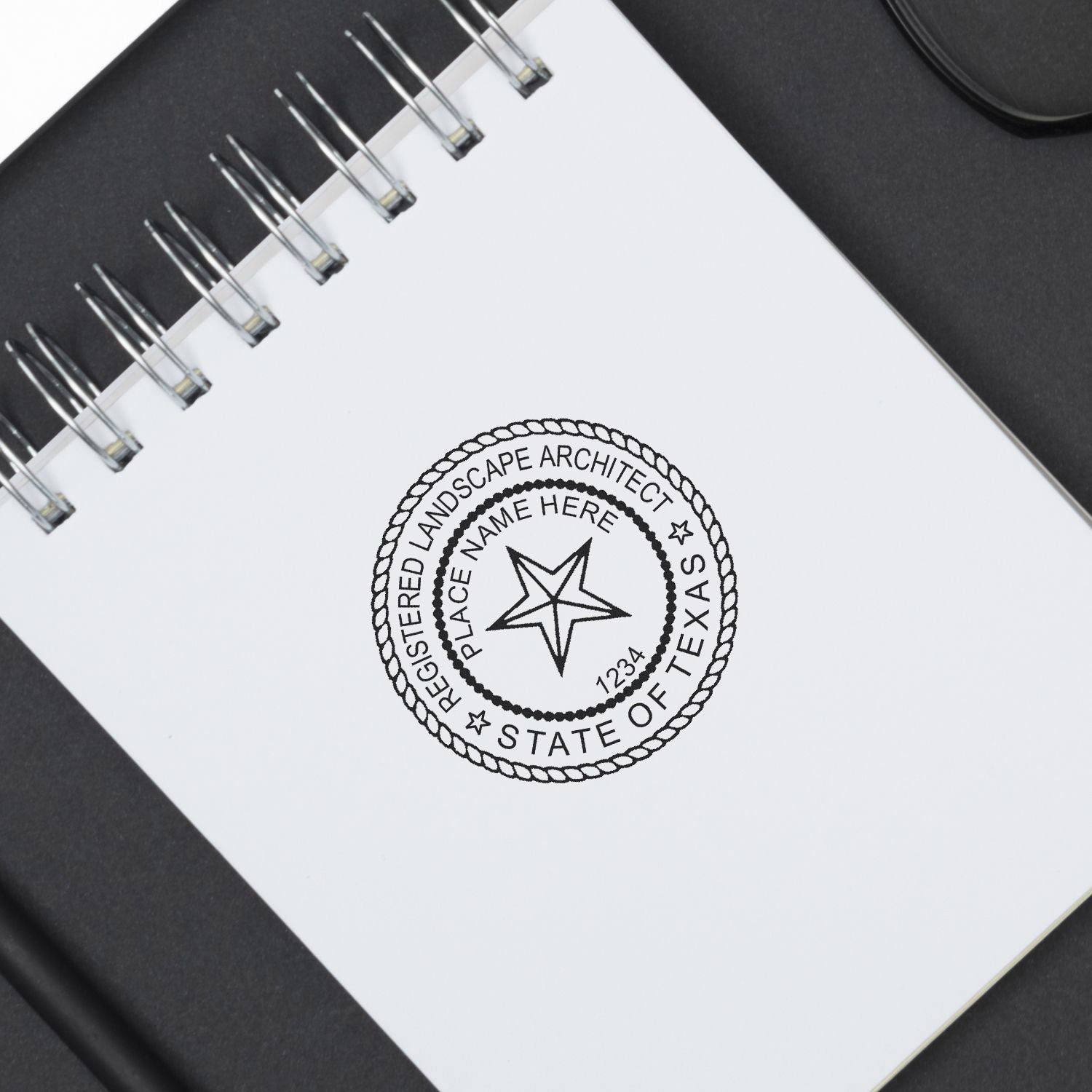 Texas Landscape Architect Feature Image: A spiral notebook with a Texas landscape architect seal stamp on a black surface.