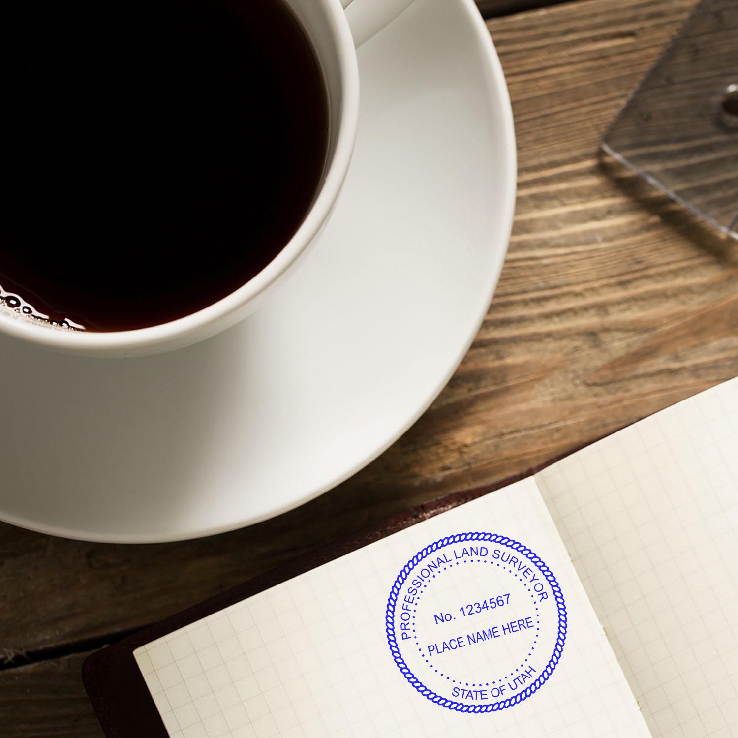 A coffee cup next to a notebook stamped with a Utah Land Surveyor Stamp. Blog post name: Utah Land Surveyor Stamp.