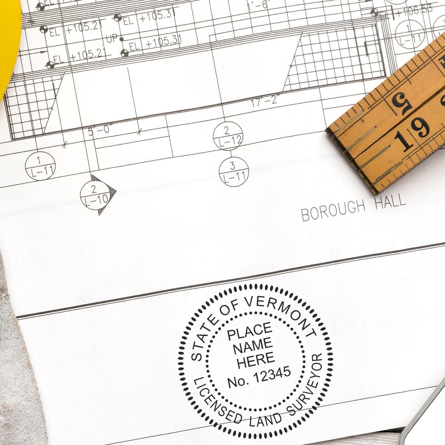 Vermont Land Surveyor Seal on a blueprint with a ruler and protractor. Blog post: Vermont Land Surveyor Seal.