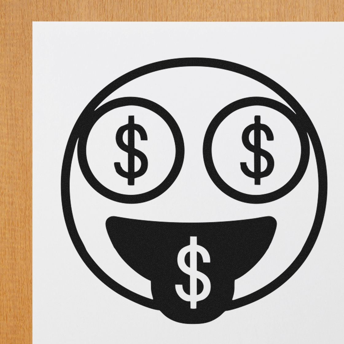 Self-Inking Money Eyes Facial Expressions Stamp featuring a smiling face with dollar signs for eyes and tongue, stamped on white paper against a wooden background. Perfect for fun, creative projects.