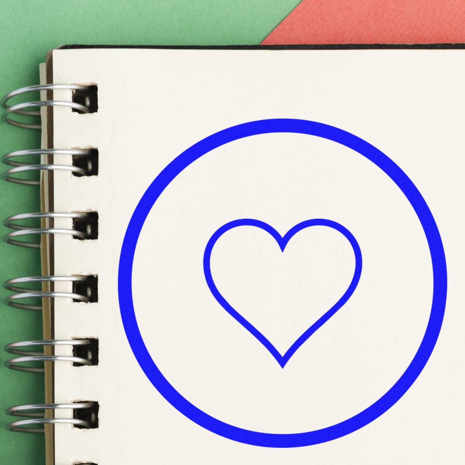 Self-Inking Heart of Simplicity Emojicons Stamp on a notebook page, featuring a blue heart outline within a circle. Perfect for adding a touch of love to your notes and crafts.