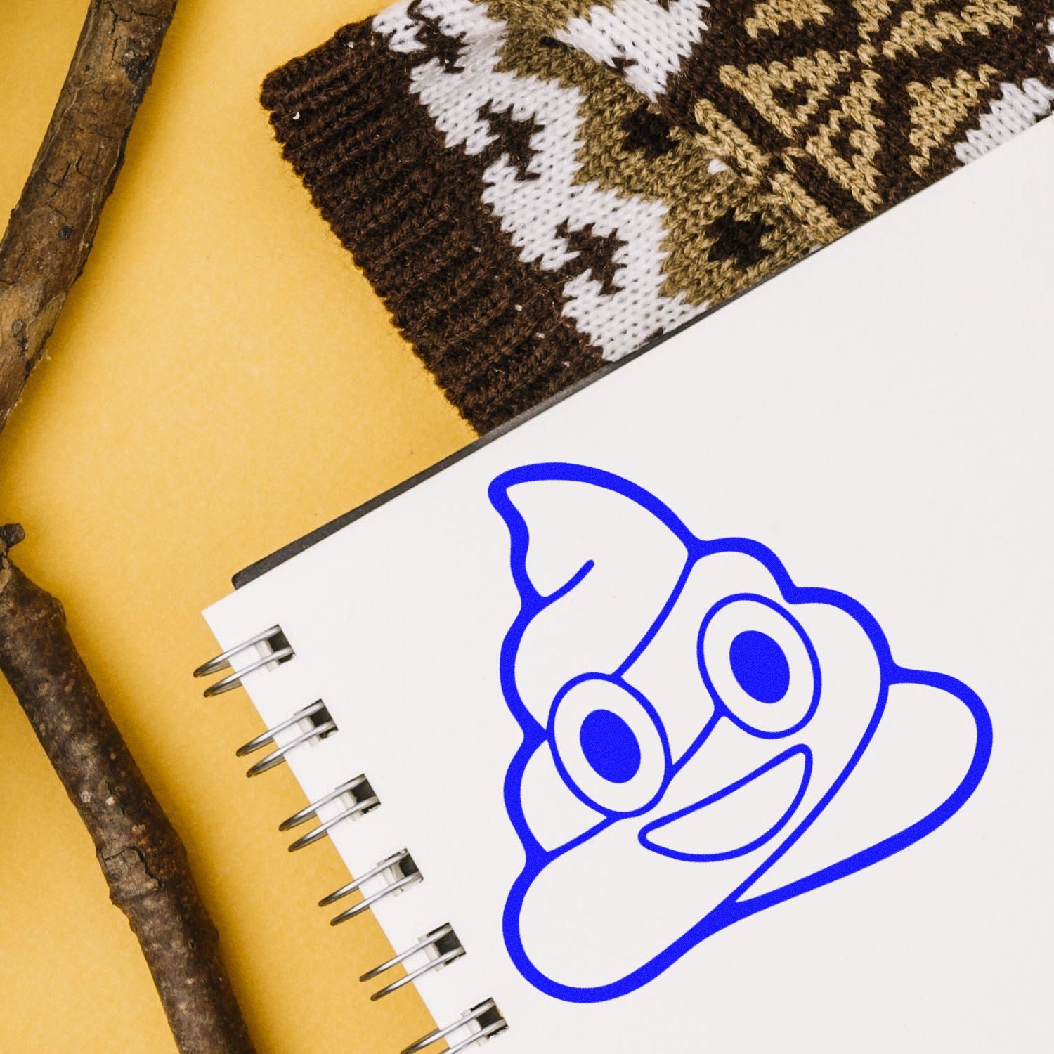 Wood Handle Poop Emoji Pal Rubber Stamp on a notebook, featuring a blue poop emoji imprint. Perfect for adding fun, quirky designs to your crafts and stationery.