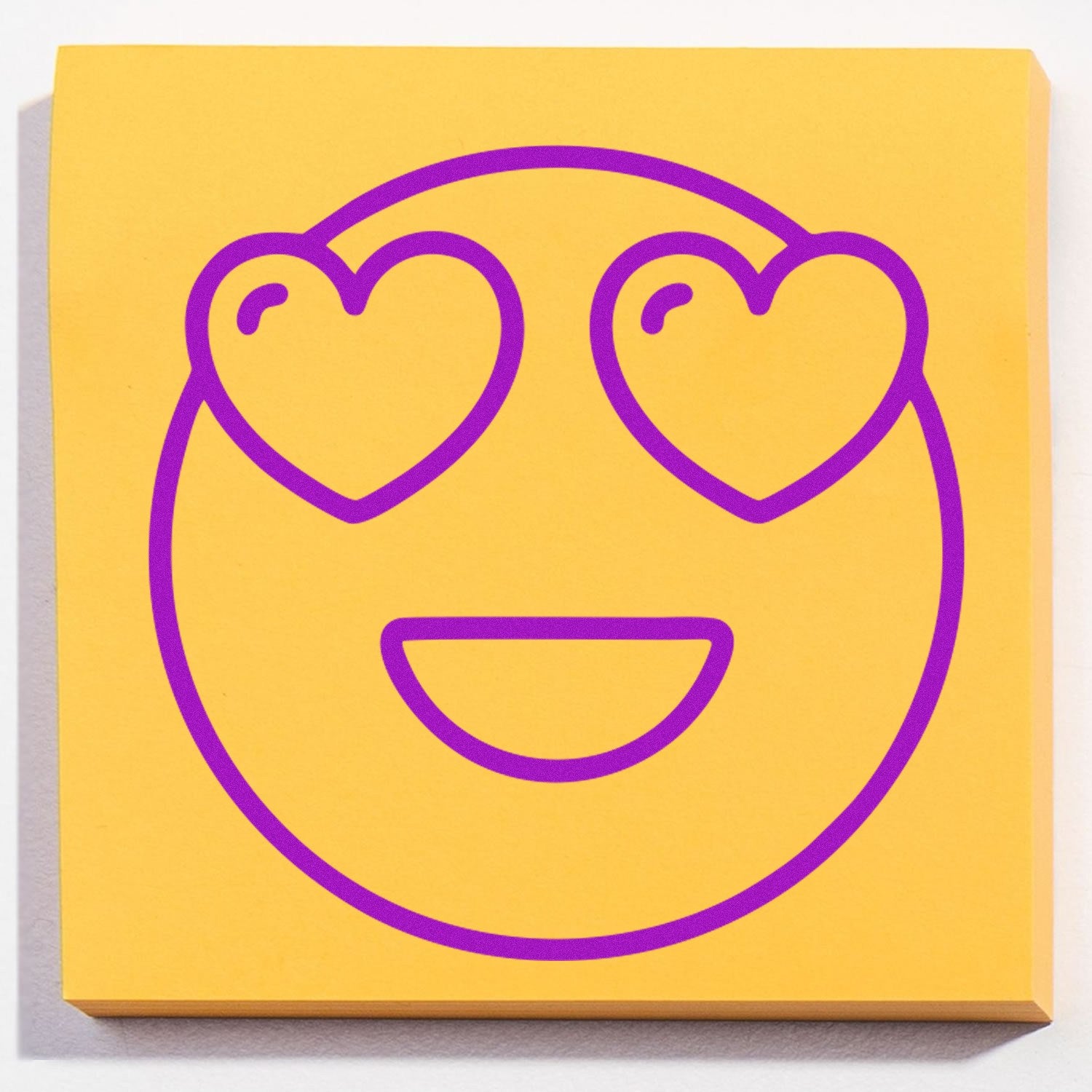 Self-Inking Love-Struck Larry Emoji Stamp featuring a purple heart-eyed smiley face on a yellow background. Perfect for adding a playful touch to notes and crafts.