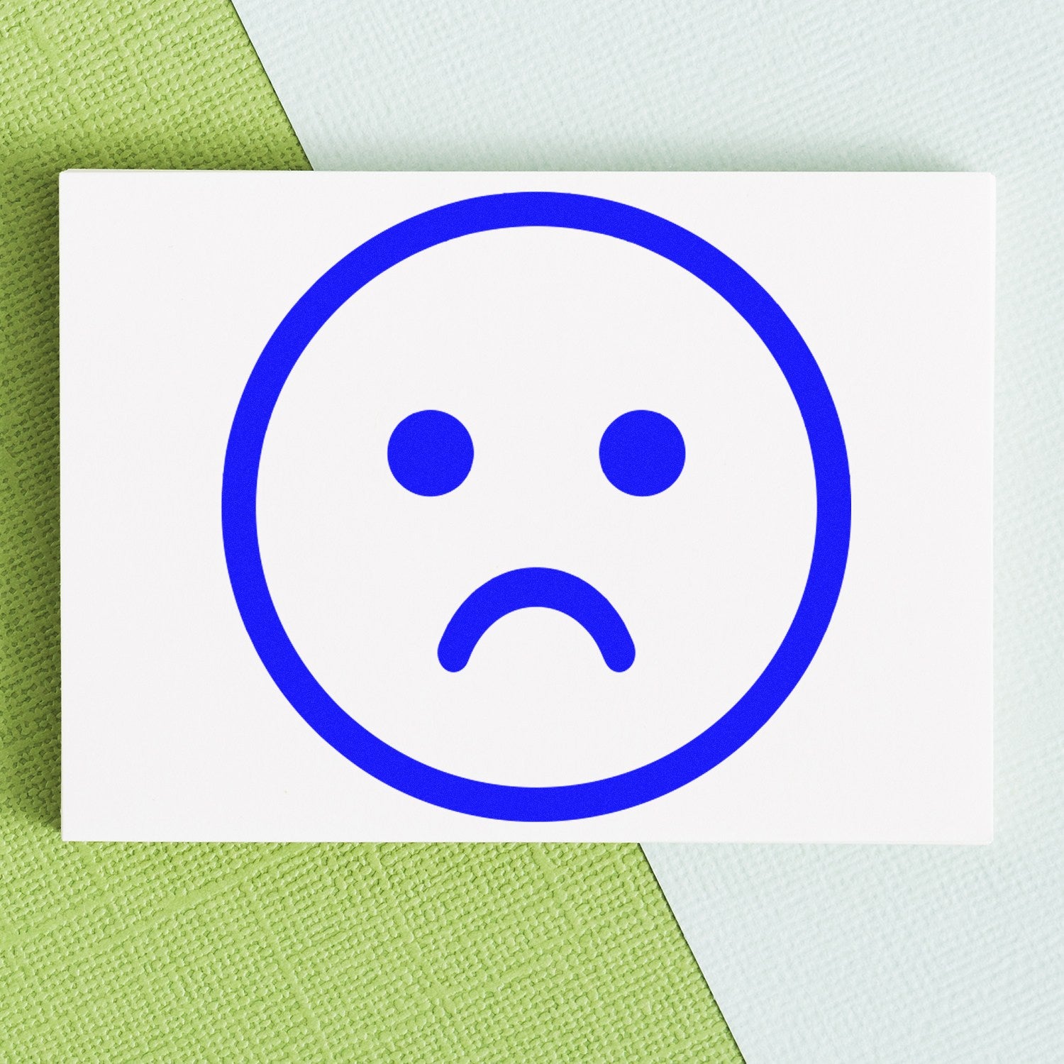 Wood Handle Sad Sam Emoticon Rubber Stamp featuring a blue sad face emoticon on a white background, perfect for adding a touch of emotion to your crafts and stationery projects.