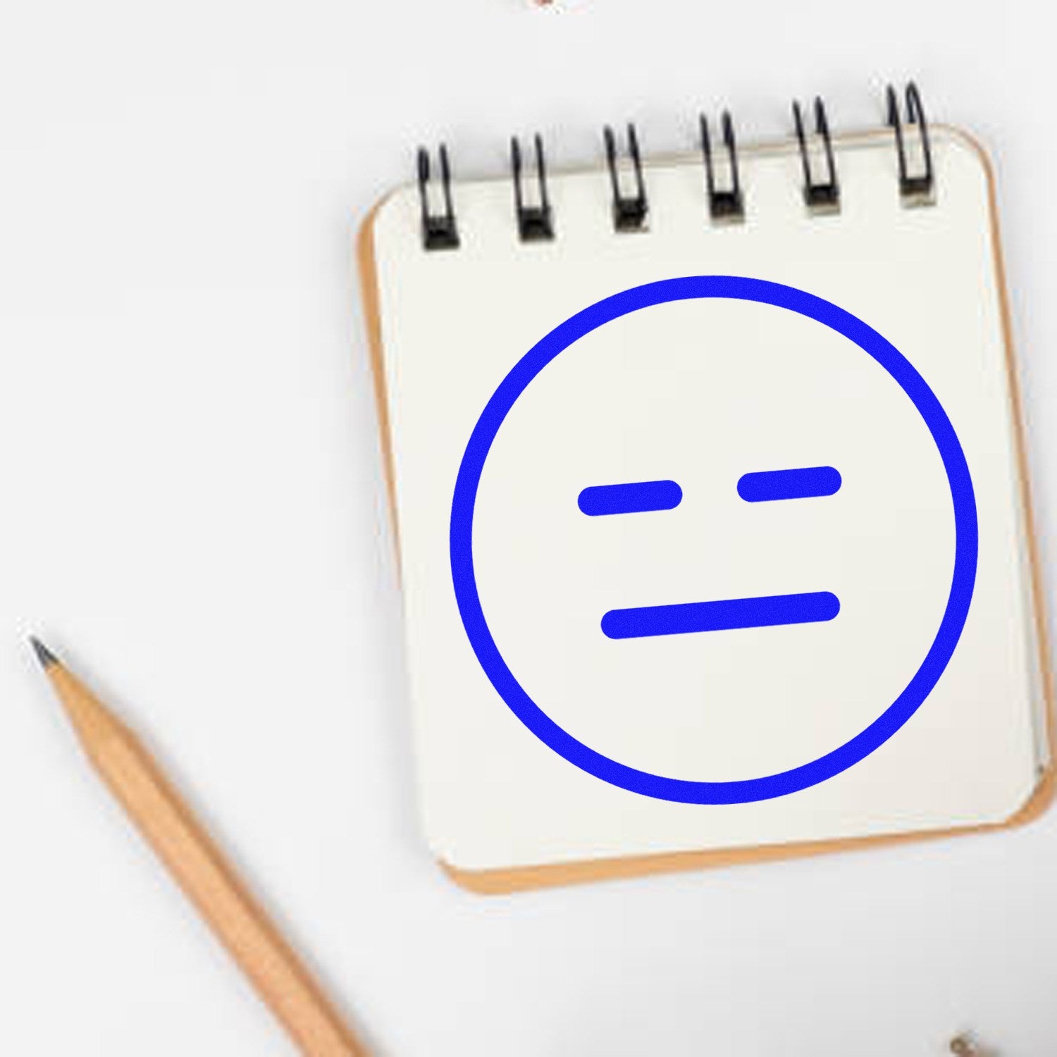 Self-Inking Expressionless Eddie Emoji Stamp on notepad, featuring a blue expressionless face. Perfect for adding a touch of humor to your notes and documents.