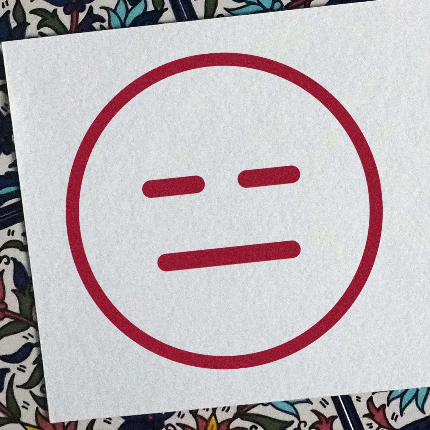 Self-Inking Expressionless Eddie Emoji Stamp on paper, featuring a simple red expressionless face. Perfect for adding a touch of humor to documents and crafts.