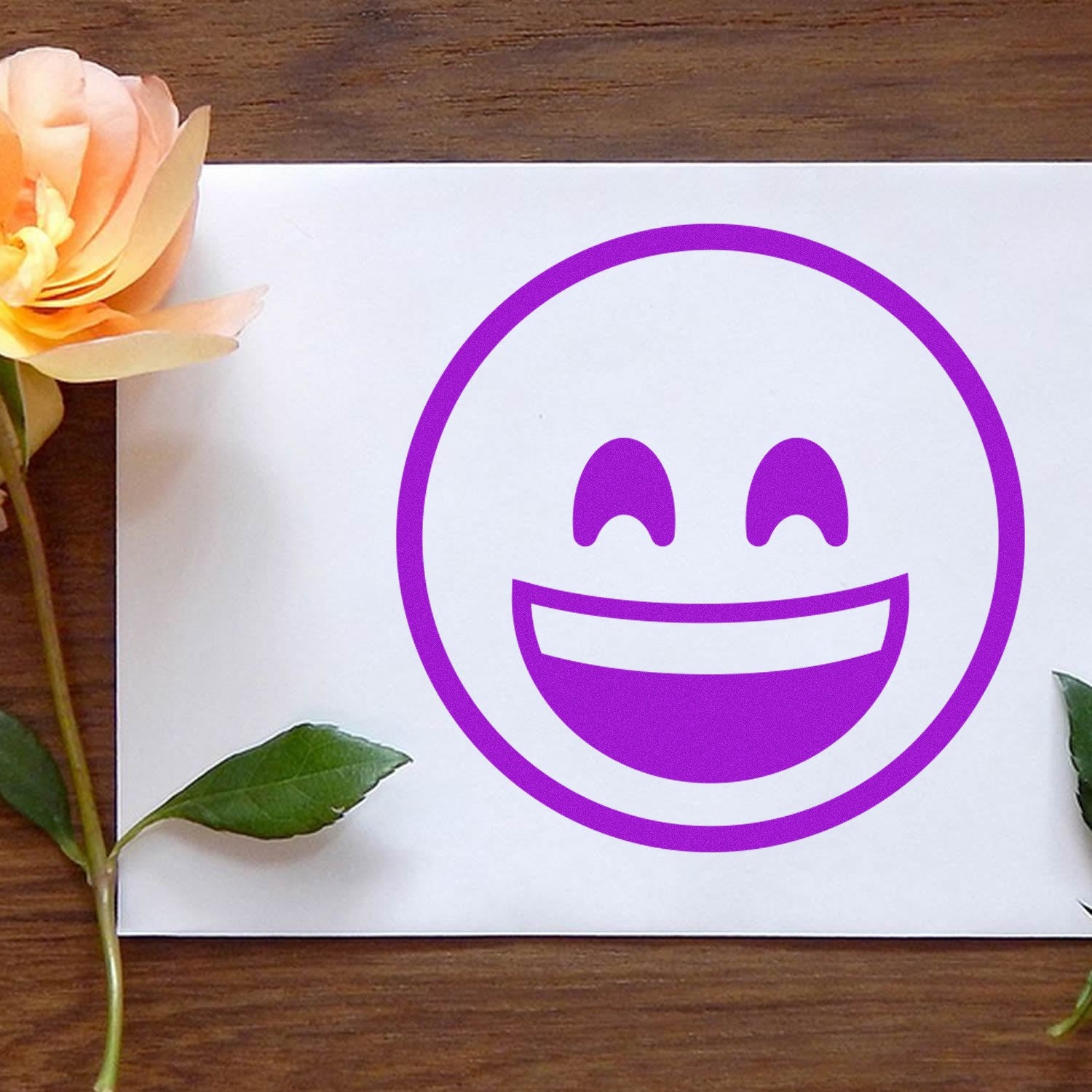 Wood Handle Ecstatic Eyes Emoji Rubber Stamp on paper, featuring a purple smiling face with closed eyes. Perfect for crafts and stationery.