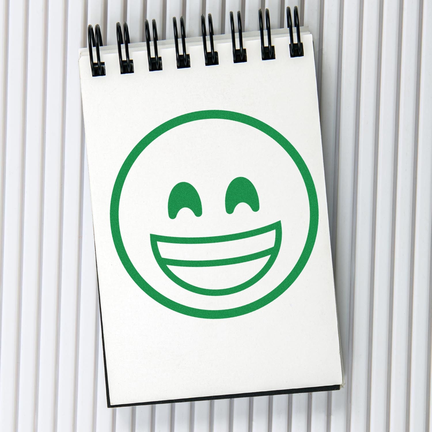 Wood Handle Elated Smile Emoji Rubber Stamp imprint on notepad, showcasing a cheerful green smiley face design. Perfect for adding a fun touch to crafts and stationery.