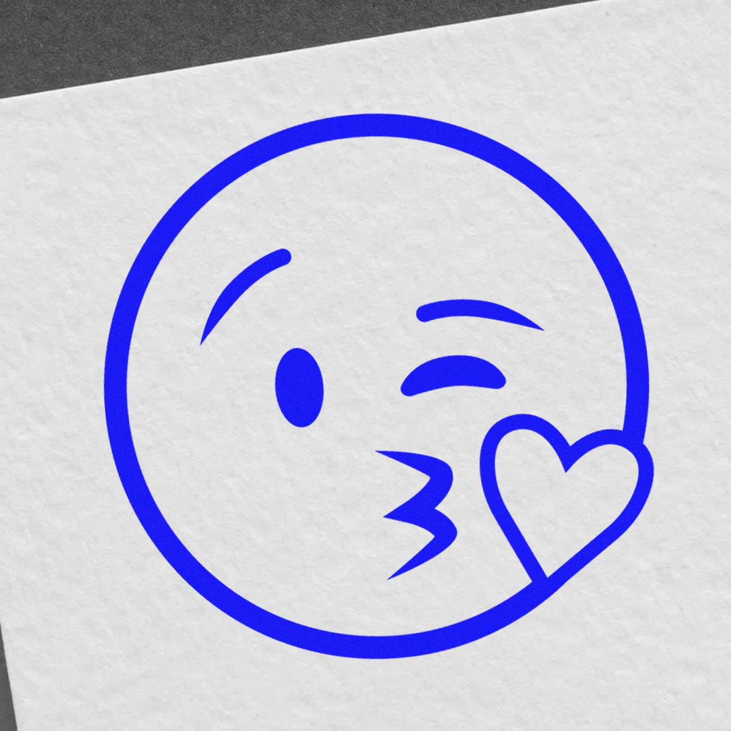 Wood Handle Blowing a Kiss Emoji Rubber Stamp on white paper, featuring a blue emoji with a winking eye and heart. Perfect for crafts, letters, and personalized gifts.