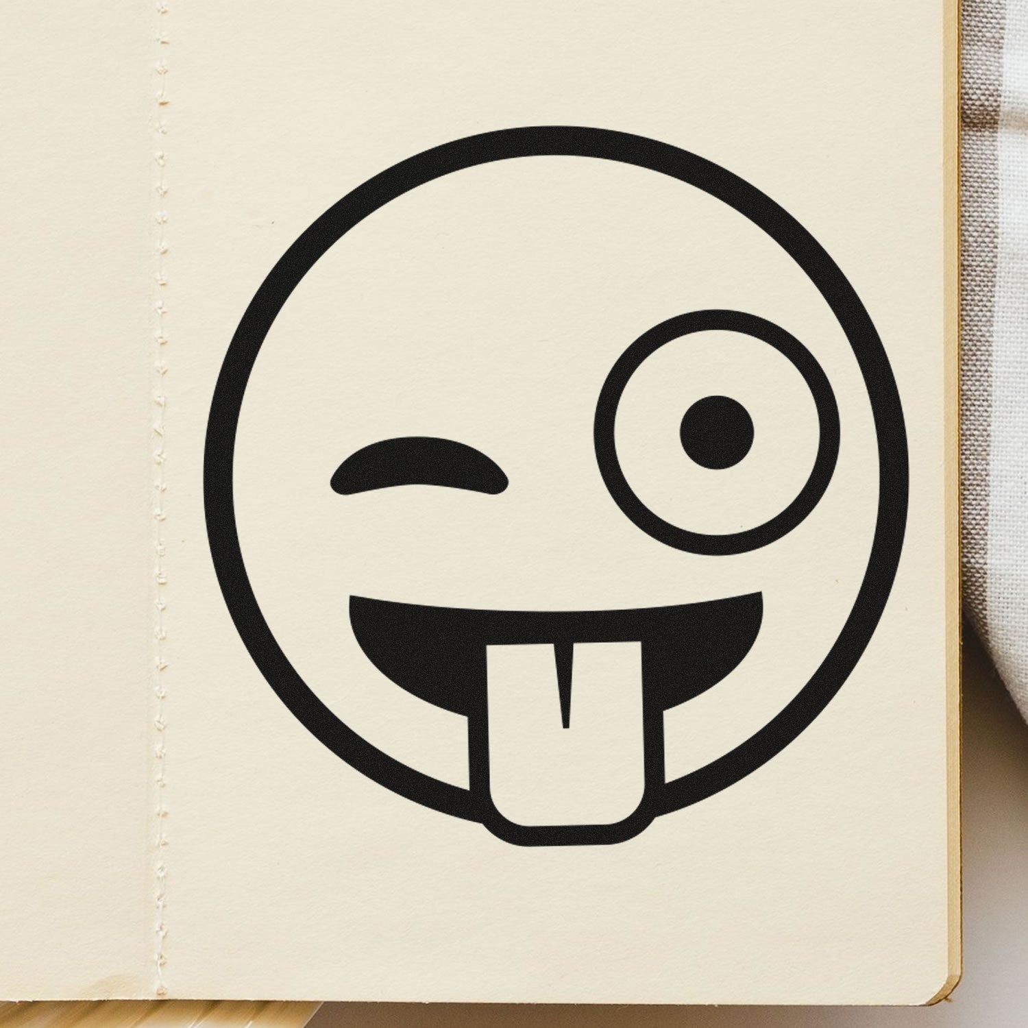 Wood Handle Goofy Wink Emoji Rubber Stamp on paper, featuring a playful wink and tongue-out design. Perfect for adding fun to crafts and stationery.