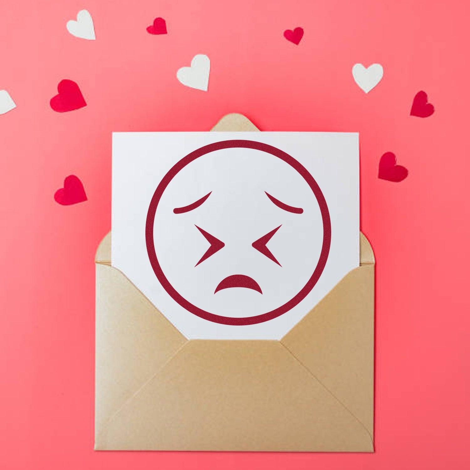 Self-Inking Starry Sadness Emoji Stamp on pink background with hearts, featuring a sad face design on a card in a brown envelope.