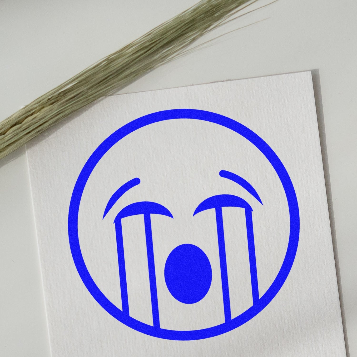 Wood Handle Waterworks Wanda Emoji Rubber Stamp imprint on white paper, featuring a blue crying emoji design, with a wooden handle visible. Perfect for crafting and personalization.