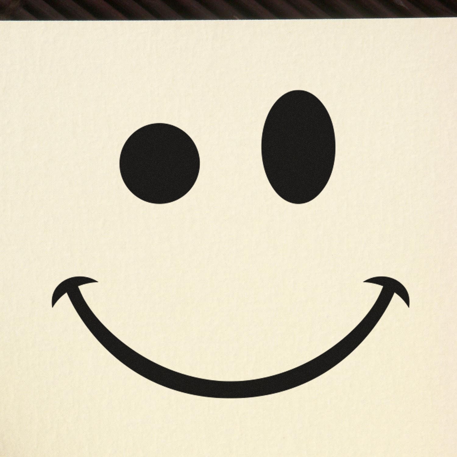 Self-Inking Mischievous Grin Emoji Stamp on paper, featuring a playful smiley face with a cheeky expression. Perfect for adding fun to notes and crafts.