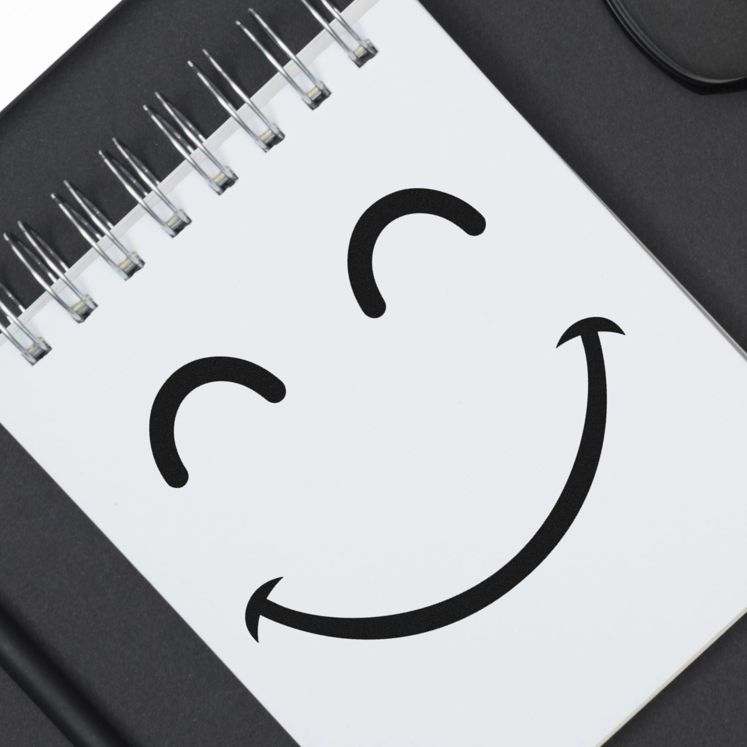 Self-Inking Giggly Smiley Emoji Stamp on a notepad, showcasing a cheerful smiley face design. Perfect for adding fun and personality to notes and documents.