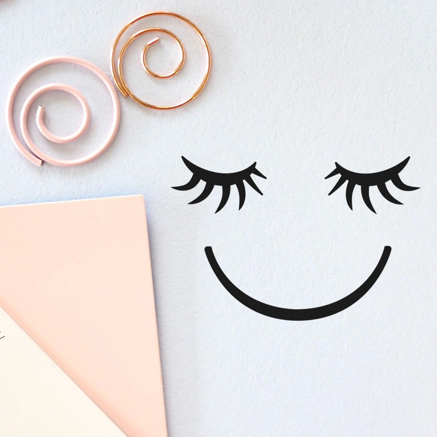 Image of the Self-Inking Dreamy Delight Pictogram Stamp featuring a smiling face with closed eyes, surrounded by pastel-colored paper and spiral decorations. Perfect for crafts and stationery.