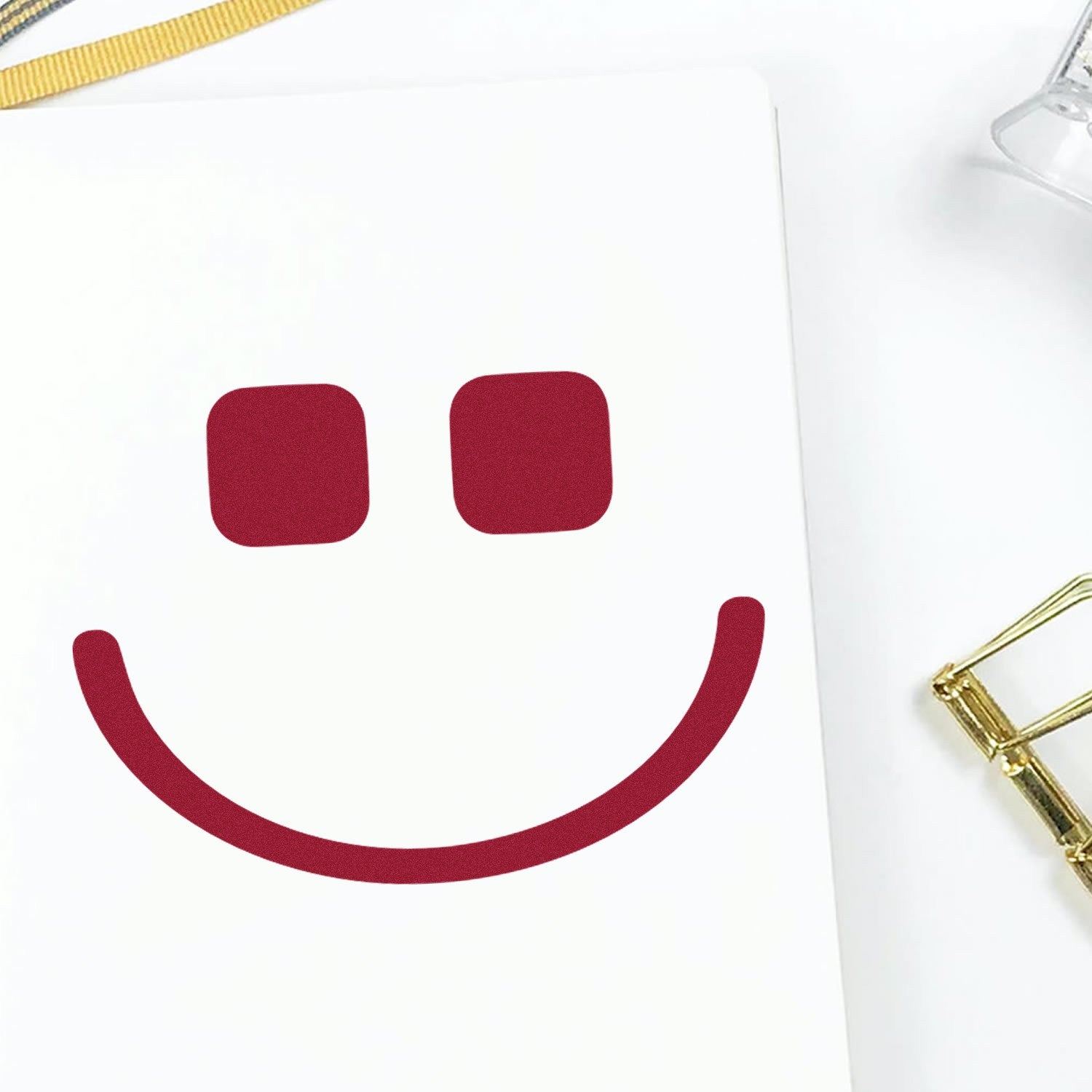 Wood Handle Geeky Grin Emotes Rubber Stamp imprint on white paper, featuring a playful red smiley face design. Ideal for adding a fun touch to crafts and stationery.