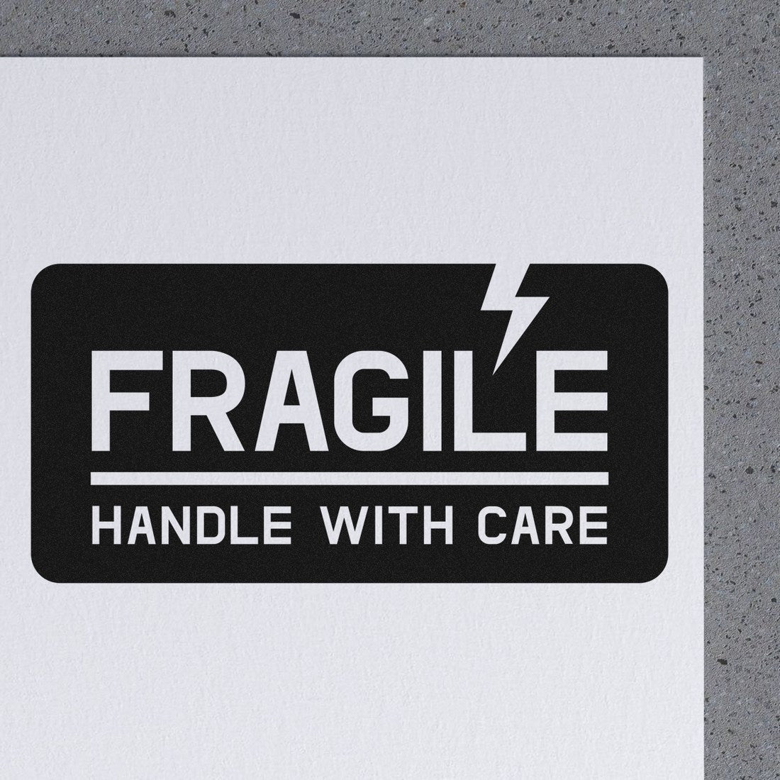 Image of Maxlight Premium Lightning Fragile Stamp on a gray surface, featuring bold FRAGILE text with a lightning bolt and HANDLE WITH CARE message, ideal for marking delicate packages.