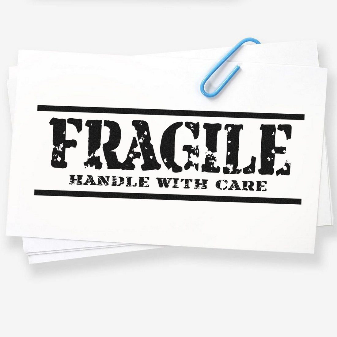 Maxlight Premium Rustic Fragile Handle With Care Stamp on white paper, featuring bold, distressed black lettering, secured with a blue paperclip. Ideal for packaging and shipping needs.