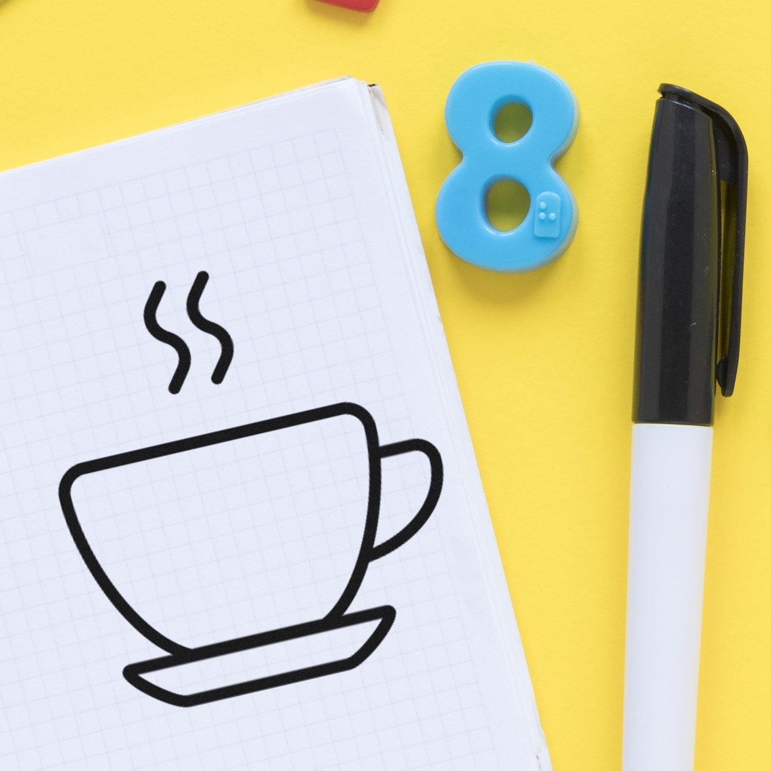 Self-Inking Steaming Coffee Cup Loyalty Stamp on notepad with black pen and blue number eight magnet on yellow background.