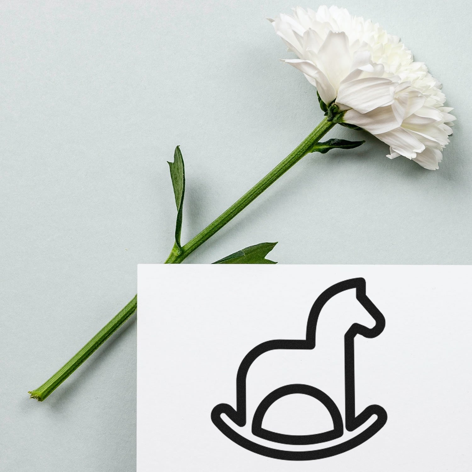 Self-Inking Rocking Horse Delight Loyalty Scheme Stamp with a black rocking horse design, shown next to a white flower on a light gray background.