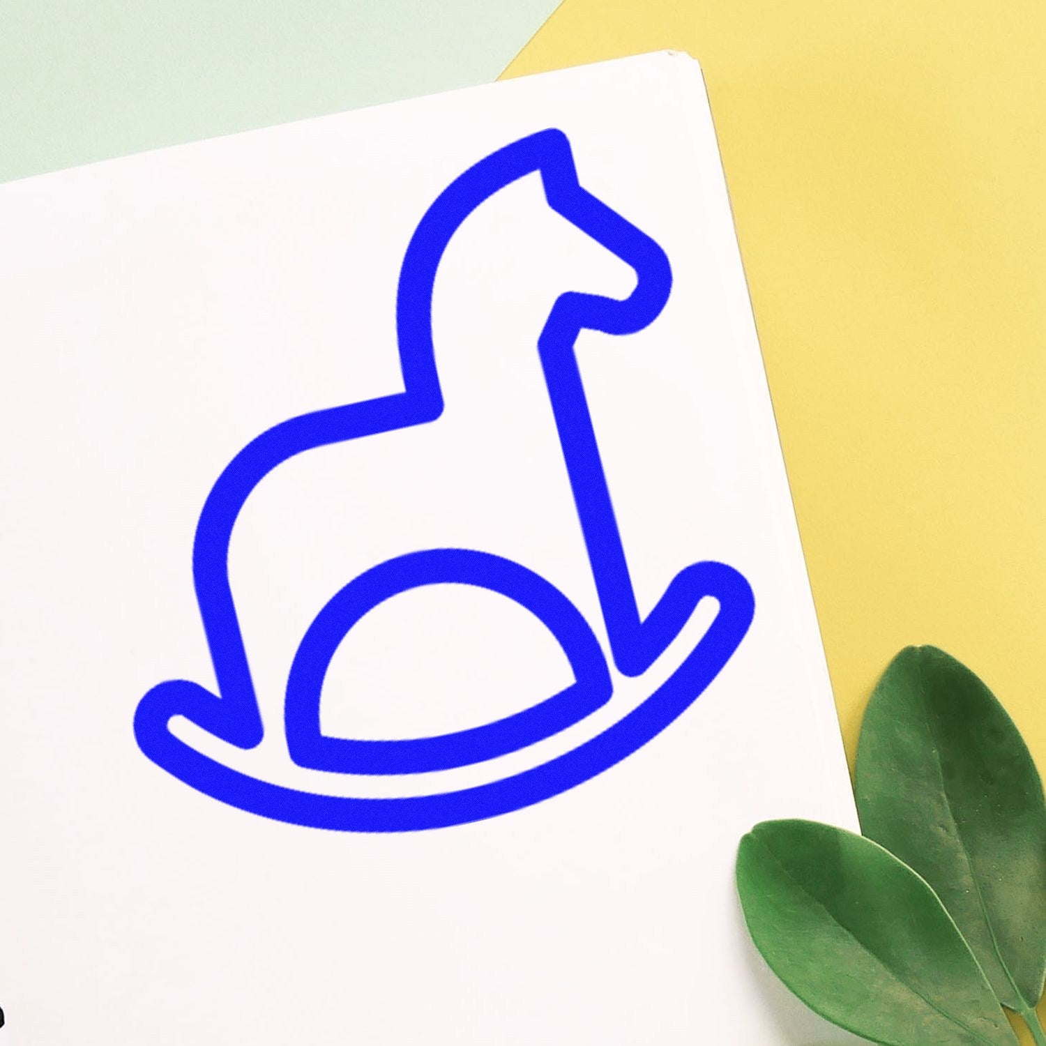 Self-Inking Rocking Horse Delight Loyalty Scheme Stamp in blue, featuring a simple rocking horse design on white paper, with green leaves and a yellow background. Perfect for loyalty programs.