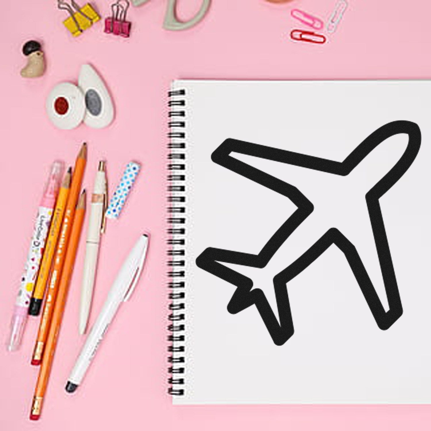 Self-Inking Jetsetter-Based Rewards Stamp on pink desk with airplane design, surrounded by pens, paper clips, and stationery. Ideal for travel-themed projects and organization.