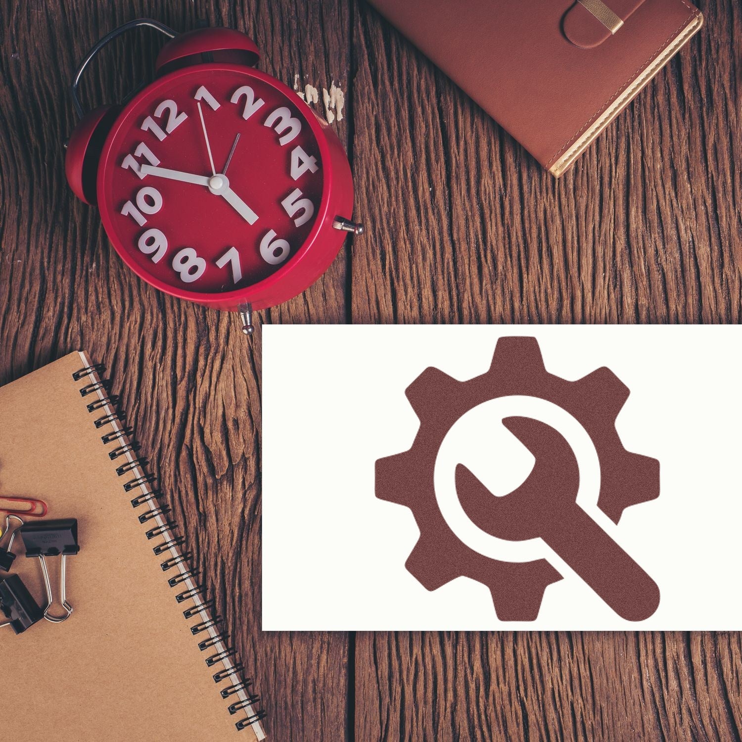 Image of a Self-Inking Tool Reward Program Stamp on a wooden desk with a red clock, notebook, and leather wallet, showcasing a gear and wrench design. Perfect for efficient stamping needs.