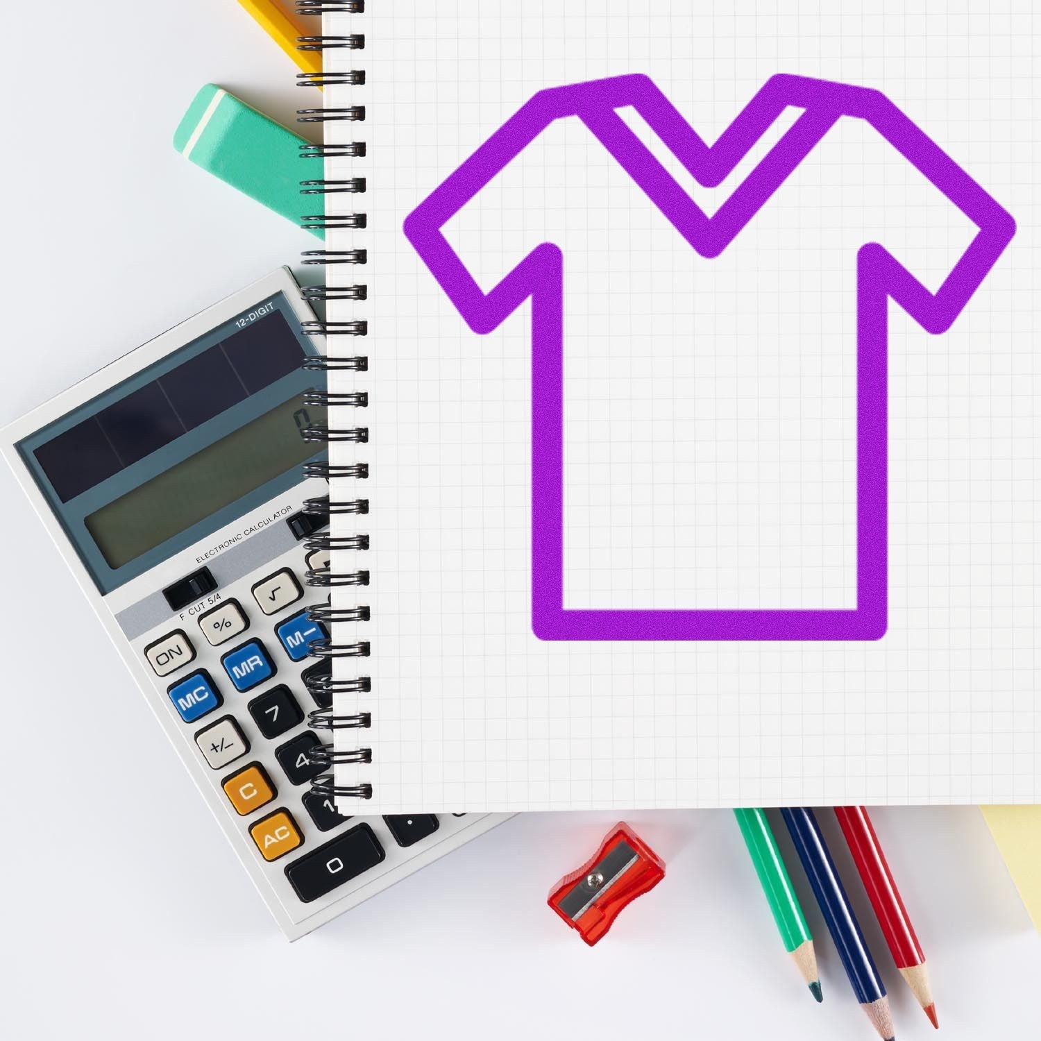 Self-Inking Clothing Frequent Buyer Stamp with a purple shirt design on a notepad, surrounded by a calculator, colored pencils, and a sharpener.