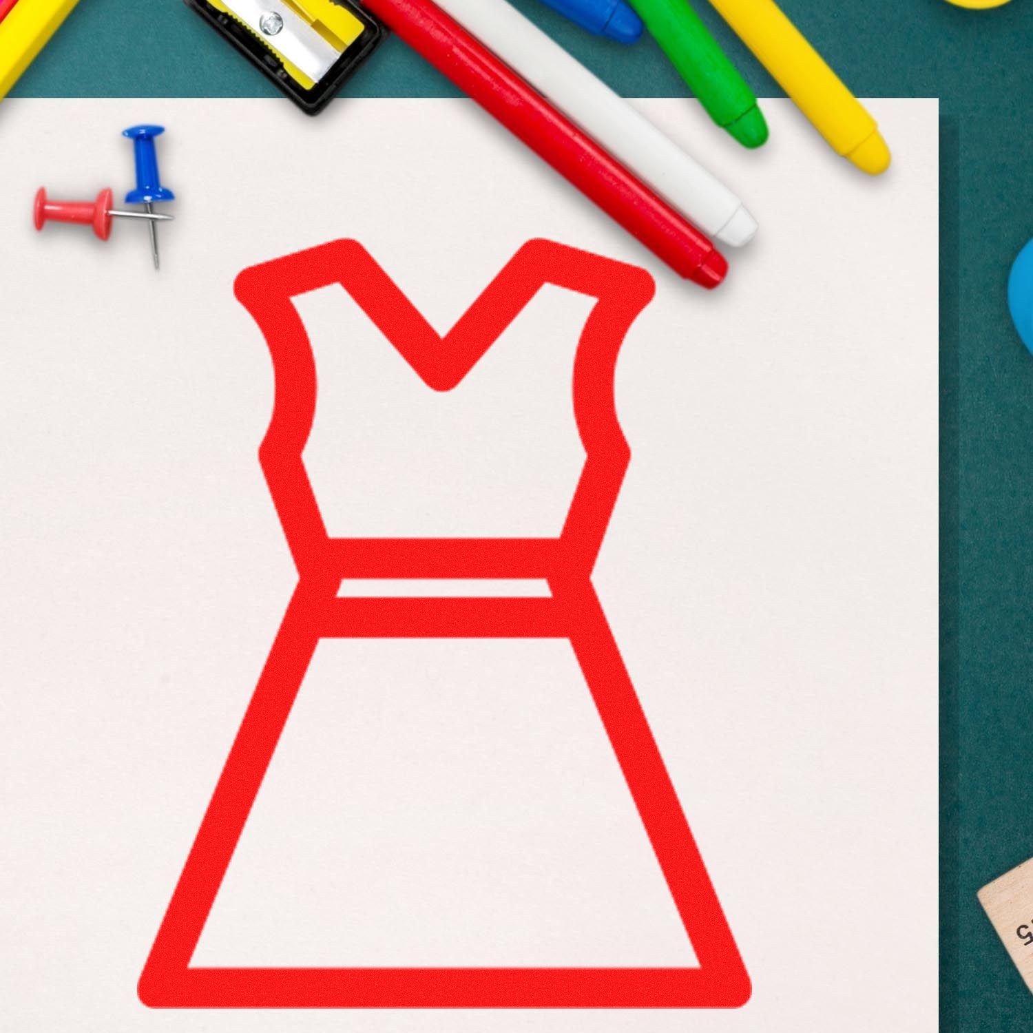 Wood Handle Clothing Punch Card Rubber Stamp featuring a red dress outline design, surrounded by colorful markers and push pins on a green surface.