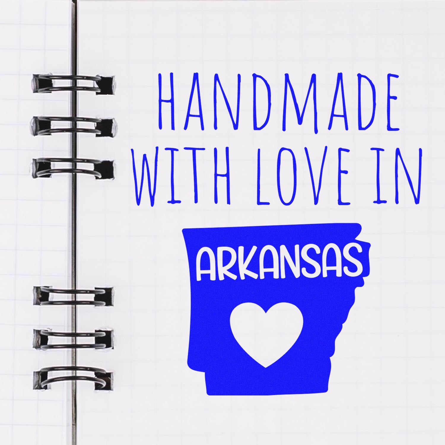 Wood Handle Arkansas Handmade with Love Rubber Stamp on a notebook page, featuring a blue design with Handmade with Love in Arkansas text and heart shape. Perfect for crafts and gifts.