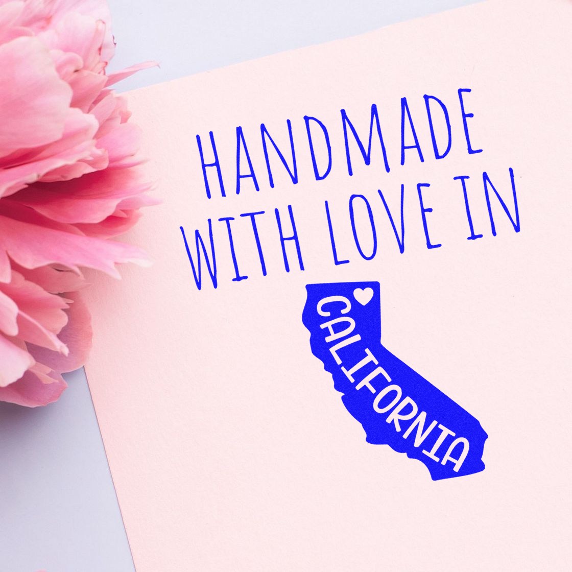 Self-Inking California Handmade with Love Stamp on pink paper with a blue California state outline and text. Perfect for crafts and gifts.