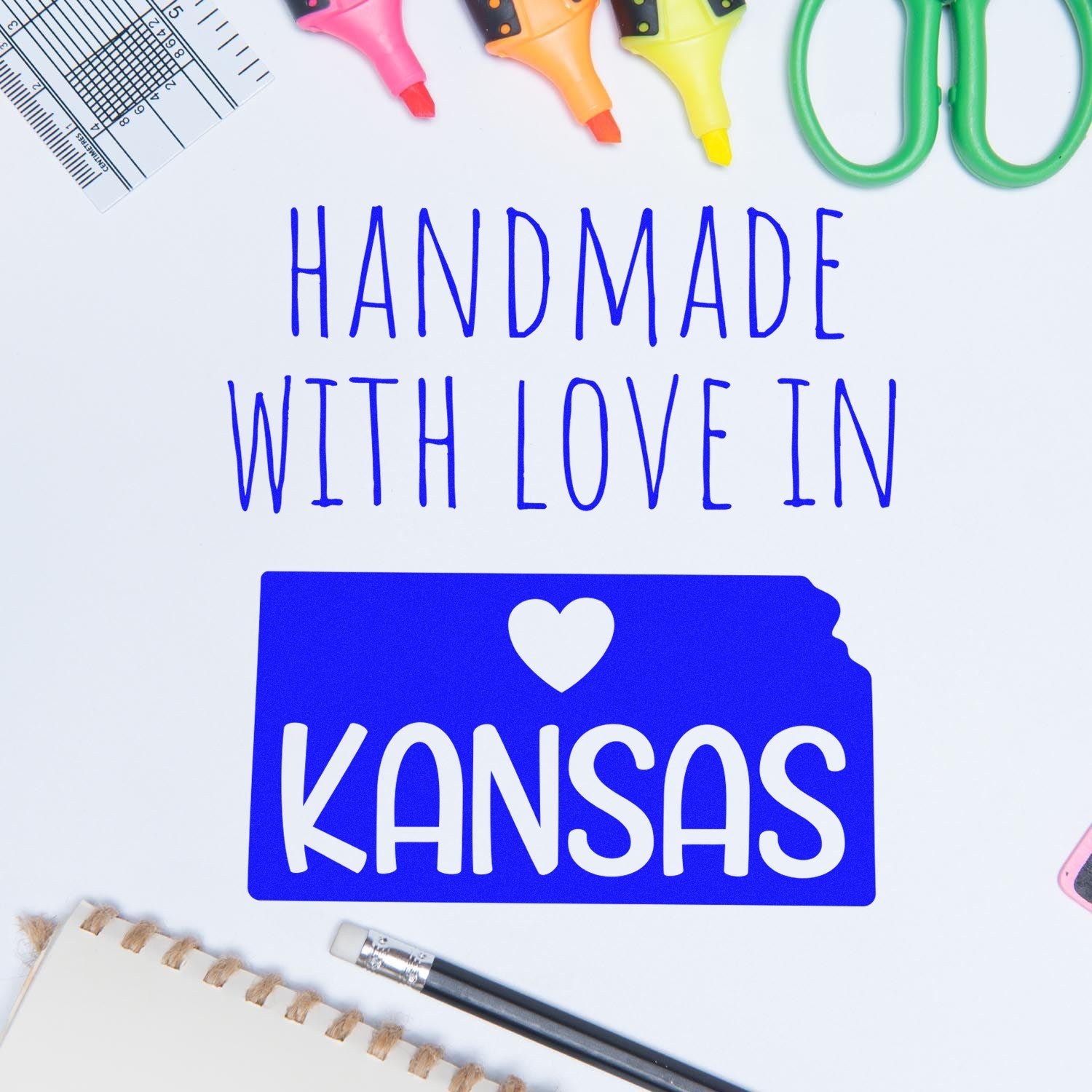 Self-Inking Kansas Handmade with Love Stamp featuring a blue Kansas state outline with a heart, surrounded by stationery items. Perfect for adding a personal touch to crafts and gifts.