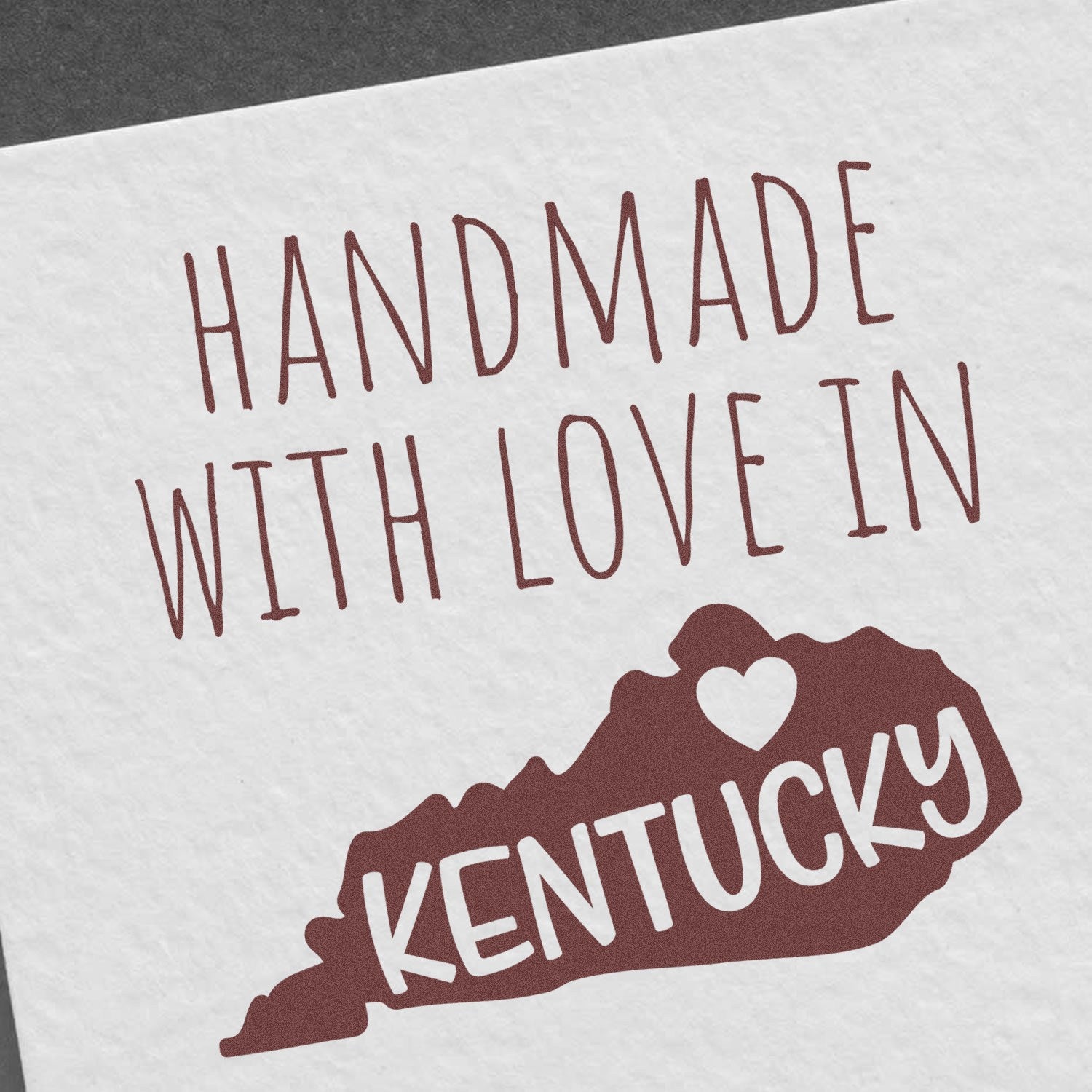 PSI Pre-Inked Handmade with Love in Kentucky stamp on white paper, featuring brown text and a heart-shaped Kentucky outline.