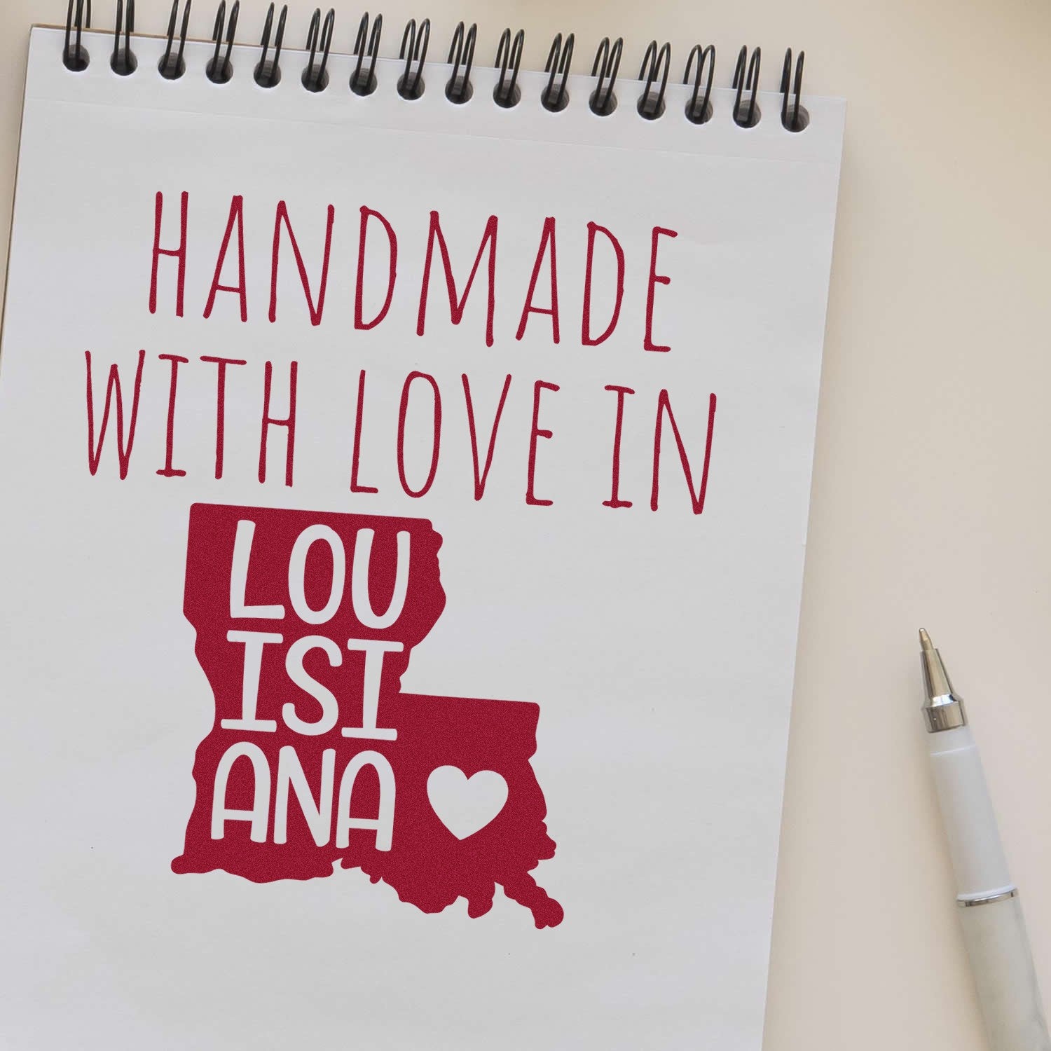 Self-Inking Louisiana Handmade with Love Stamp on notepad, featuring red text and state outline with heart, showcasing craftsmanship and state pride.