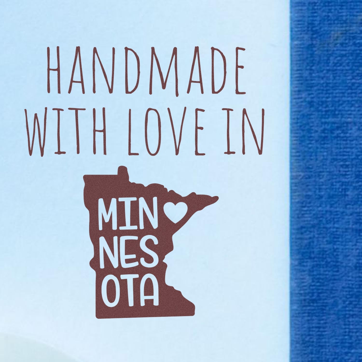 Handmade with Love in Minnesota Slim Pre-Inked Stamp featuring a heart and state outline design on a blue background.