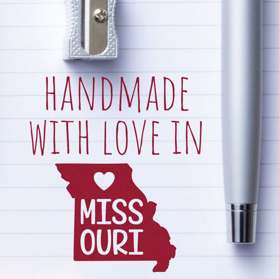 Handmade with Love in Missouri Slim Pre-Inked Stamp on lined paper with a silver pen and sharpener, showcasing a heart within the state outline. Perfect for personalized stationery.