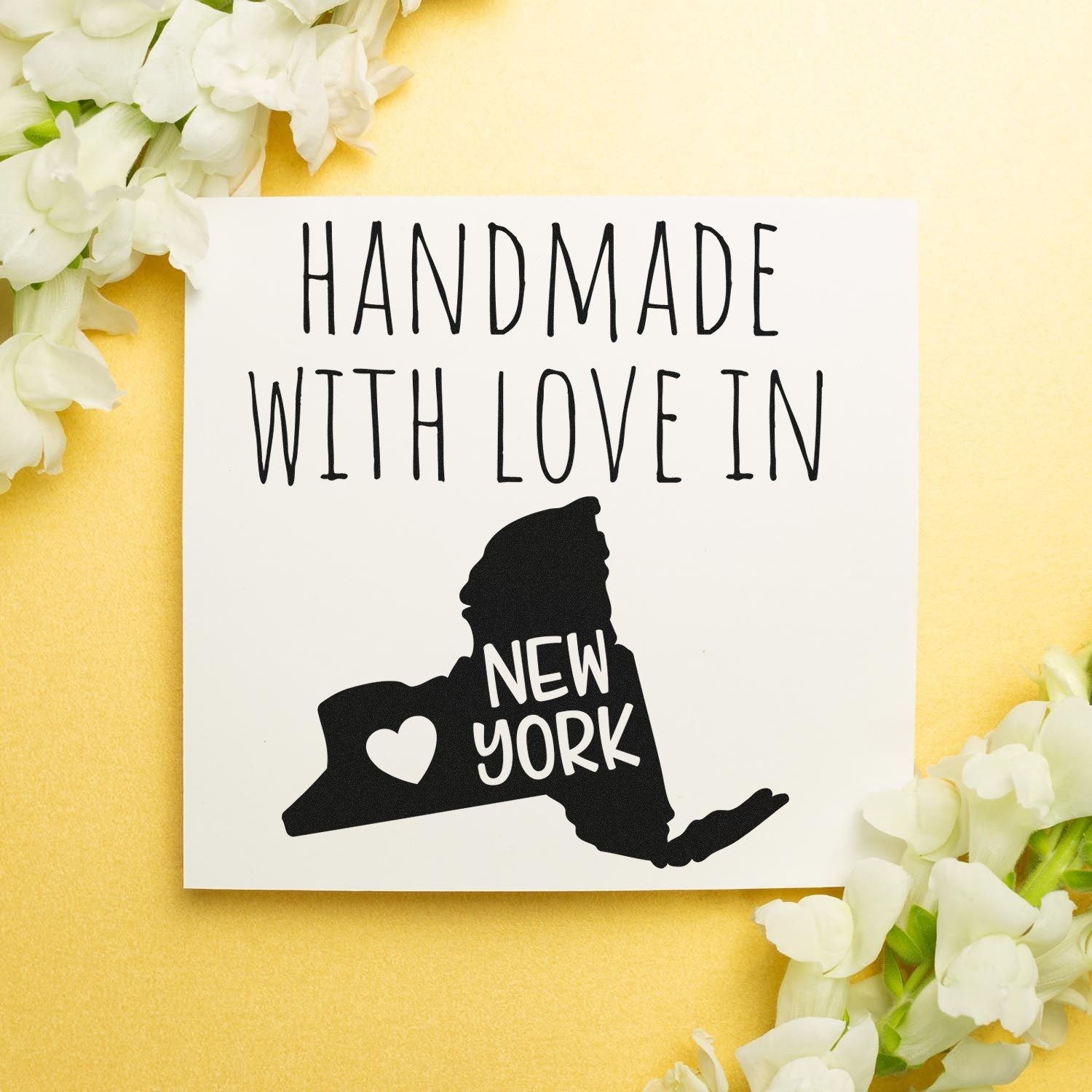 Wood Handle New York Handmade with Love Rubber Stamp on a card with New York state outline and heart, surrounded by white flowers on a gold background.